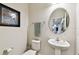 Stylish powder room with a pedestal sink, decorative mirror, and an eye-catching framed painting at 8368 Greenway Ave, Wesley Chapel, FL 33544