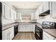 Kitchen with white cabinets, black appliances, and a double sink under a window at 1120 Andrew Aviles Cir, Tampa, FL 33619