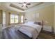 Serene main bedroom with tray ceiling, neutral tones, and large windows for natural light at 16122 Cedar Key Dr, Wimauma, FL 33598