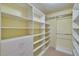 Walk-in closet with custom white shelves and drawers and beige carpet at 25622 Ferdinand Ct, Wesley Chapel, FL 33544