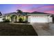 Charming single-story home with arched entryway, two-car garage, and tropical landscaping at dusk at 5366 Hader Rd, North Port, FL 34288