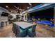 Covered outdoor dining area with ample seating next to a stunning pool and kitchen at 335 Bath Club S Blvd, North Redington Beach, FL 33708