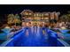 Luxury home featuring a lit pool, fire bowls, and tropical landscaping at night at 335 Bath Club S Blvd, North Redington Beach, FL 33708