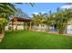 Inviting backyard patio area with a wooden pergola, lush green turf, tropical landscaping, and a pool in the background at 4210 Harrisburg Ne St, St Petersburg, FL 33703