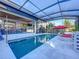 Inviting screened pool area featuring lounge chairs and a red umbrella for relaxing by the pool at 818 W Adalee St, Tampa, FL 33603