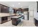 Spacious kitchen features dark cabinets, stainless appliances, granite countertops, and tile flooring at 19724 Post Island Loop, Land O Lakes, FL 34638