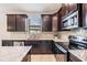Close-up of kitchen with stainless steel appliances, dark cabinets, and granite countertops at 19724 Post Island Loop, Land O Lakes, FL 34638