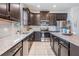 Modern kitchen with stainless steel appliances, dark wood cabinetry, tile backsplash, and granite countertops at 19724 Post Island Loop, Land O Lakes, FL 34638
