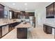 Spacious kitchen features dark cabinets, stainless appliances, granite countertops, and tile flooring at 19724 Post Island Loop, Land O Lakes, FL 34638