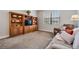 Cozy living room area with carpet flooring, a large window, comfortable seating, and custom wooden shelving at 19724 Post Island Loop, Land O Lakes, FL 34638