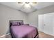 Cozy bedroom with neutral walls, a ceiling fan, and a comfortable-looking bed with purple bedding at 4506 Mapletree Loop, Wesley Chapel, FL 33544