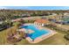 Aerial view of a spacious community pool with ample seating, a clubhouse, and nearby playground at 4506 Mapletree Loop, Wesley Chapel, FL 33544