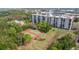 Aerial view of condo building with tennis courts, pool, landscaping, and parking lot at 5400 Park N St # 209, St Petersburg, FL 33709