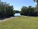 A lawn leads to a sandy beach and calm water, surrounded by lush greenery at 5400 Park N St # 209, St Petersburg, FL 33709