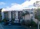 Condominium building exterior featuring balconies, parking, and landscaping, under a blue sky with scattered clouds at 90 S Highland Ave # 423, Tarpon Springs, FL 34689