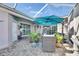 Relaxing outdoor patio area featuring comfortable seating, a blue umbrella, and decorative potted plants at 204 Latitude Pl, Apollo Beach, FL 33572