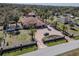 Aerial view of gated estate with a large home, terra cotta roof, and a matching detached garage at 27826 Robin Roost Ln, Wesley Chapel, FL 33544