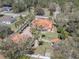 Sprawling estate with a terra cotta roof, mature trees, a white fence, and a patterned brick driveway at 27826 Robin Roost Ln, Wesley Chapel, FL 33544