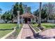 Picturesque backyard gazebo with a red tile roof, lush lawn, and landscaped surroundings at 27826 Robin Roost Ln, Wesley Chapel, FL 33544