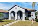 Welcoming home exterior showcasing arched entryway, light-grey stucco facade and landscaped front yard at 4209 Amber Ridge Ln, Valrico, FL 33594