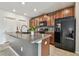 A kitchen featuring a granite counter island, tile floors, wooden cabinets, and a black refrigerator at 11127 Hudson Hills Ln, Riverview, FL 33579