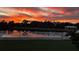A picturesque pond view at sunset, framed by a white fence and lush greenery at 11127 Hudson Hills Ln, Riverview, FL 33579