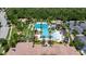 Aerial view of pool with water slide, tennis courts, clubhouse, parking and a beautiful landscape at 4899 Isola Ct, Wesley Chapel, FL 33543