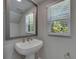 Bathroom with a pedestal sink, a silver-framed mirror, and a window offering natural light at 4899 Isola Ct, Wesley Chapel, FL 33543