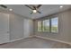 Bedroom with light grey walls, three windows, and a ceiling fan at 4899 Isola Ct, Wesley Chapel, FL 33543