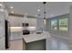 This kitchen features white cabinets, stainless steel appliances, a center island, and pendant lights at 4899 Isola Ct, Wesley Chapel, FL 33543