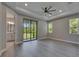 Main bedroom featuring gray wood floors, recessed lights, tray ceiling, and balcony access at 4899 Isola Ct, Wesley Chapel, FL 33543