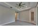 Primary bedroom featuring tray ceiling, fan, and access to a bathroom and balcony at 4899 Isola Ct, Wesley Chapel, FL 33543