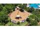 Aerial view of a community playground with slides, swings, and picnic tables surrounded by lush green trees at 4899 Isola Ct, Wesley Chapel, FL 33543
