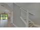 Bright foyer showcasing a modern staircase with white railings and views of an open-concept living area and backyard at 4899 Isola Ct, Wesley Chapel, FL 33543