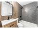 Modern bathroom with wood accent wall, updated vanity, gray tiled shower, and tub at 8703 Driftwood Dr, Tampa, FL 33615