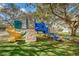 Colorful playground features slides, climbing walls, and platforms under large shade trees at 1120 Idlewild N Dr, Dunedin, FL 34698