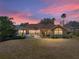 Exterior view of a home with a screened-in pool and lush landscaping at sunset at 12700 Grand Traverse Dr, Dade City, FL 33525