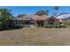 Spacious backyard with lush green lawn, mature trees, a screened in lanai, and a pool area perfect for outdoor entertaining at 12700 Grand Traverse Dr, Dade City, FL 33525