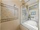 Shower and tub combination featuring decorative tile and a charming window with blinds at 12700 Grand Traverse Dr, Dade City, FL 33525