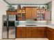 Kitchen showcasing wooden cabinetry, tile backsplash, stainless refrigerator, and granite countertops at 12700 Grand Traverse Dr, Dade City, FL 33525