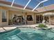 Relaxing backyard pool area featuring covered patio with ceiling fan, lounge chairs, and lush green plants in the planters at 12700 Grand Traverse Dr, Dade City, FL 33525