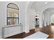 Hallway with arched window, white walls, hardwood floors, and a decorative console table at 4902 Carranza Ct, Tampa, FL 33616