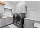 Modern laundry room with gray cabinets, quartz counters, washer, dryer, and ample storage at 4902 Carranza Ct, Tampa, FL 33616