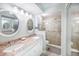 Well-lit bathroom with dual sinks, granite countertops, white cabinets, and a glass-enclosed shower at 7520 Sunshine Skyway S Ln # T18, St Petersburg, FL 33711