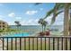 Balcony view featuring a sparkling community pool, swaying palms, and waterfront views at 7520 Sunshine Skyway S Ln # T18, St Petersburg, FL 33711