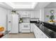 A well-lit kitchen featuring white appliances, white cabinetry, and black countertops at 2617 Cove Cay Dr # 604, Clearwater, FL 33760