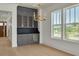 Dining area with elegant chandelier, gray built-in cabinets and wine fridge with view of street outside the windows at 323 Appian Ne Way, St Petersburg, FL 33704