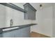 Modern laundry room featuring custom gray cabinetry, a black countertop, and stylish wood paneling at 323 Appian Ne Way, St Petersburg, FL 33704