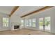 Sunlit living room with a cozy fireplace, wood beam ceiling, and double doors to the porch at 323 Appian Ne Way, St Petersburg, FL 33704