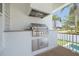 State-of-the-art outdoor kitchen with stainless steel grill, perfect for entertaining with views of the pool and palm trees at 323 Appian Ne Way, St Petersburg, FL 33704